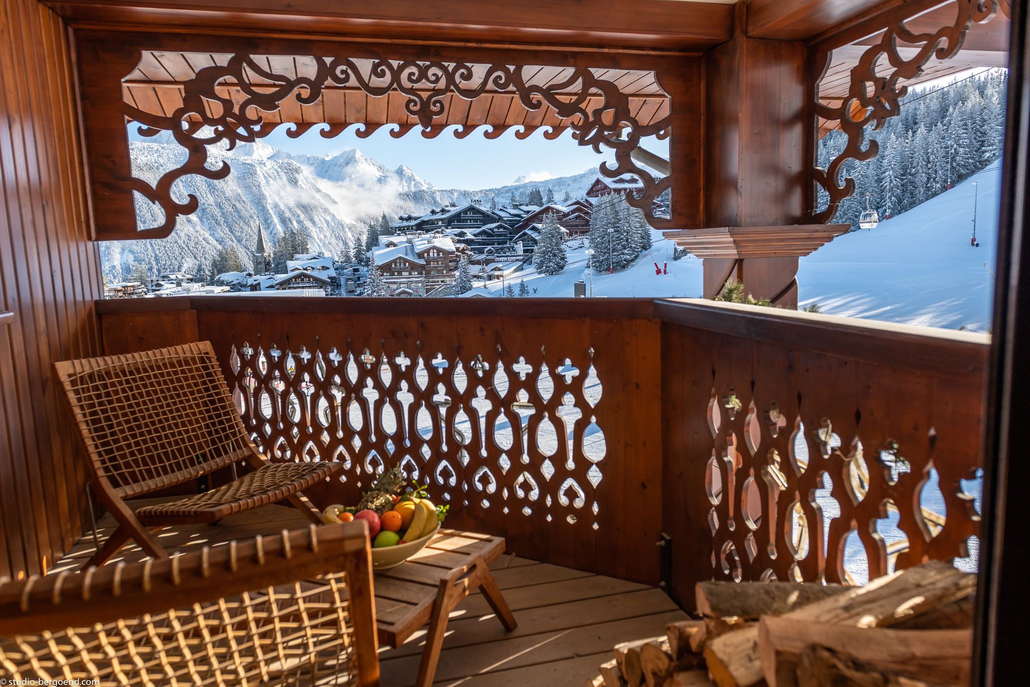 Carved wooden balcony overlooking the snowy rooftops of Courchevel 1850