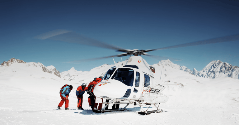 Heliskiing: skiers and helicopter on a snowy Alpine summit
